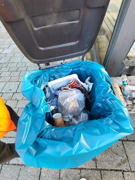 Bild vom Kreuzplatz, bevor der Bauhof aufgeräumt hat; der Mülleimer für Eisbecher ist mit Hausmüll gefüllt (Stadt Mengen)
