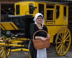 Marie Antoinettes Kammerzofe vor der historischen Postkutsche
